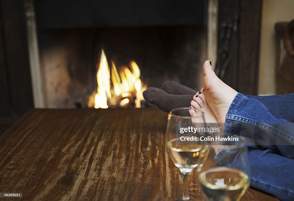 Couple warming feet in front of fire