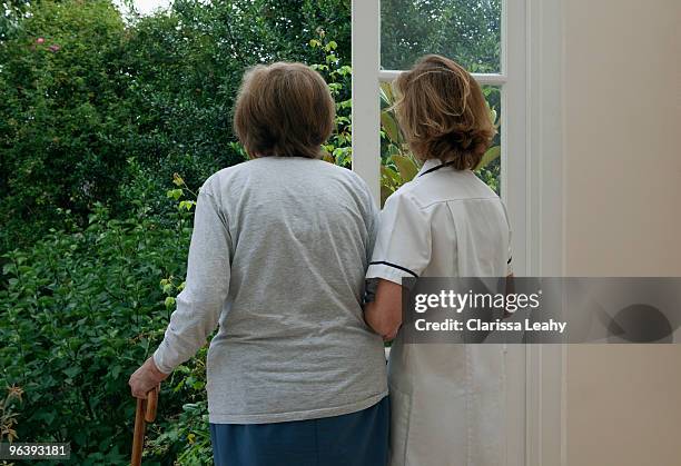 nurse supporting elderly woman - old person with walking stick outside standing stock pictures, royalty-free photos & images