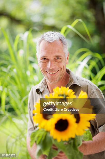 outdoor portrait of a man and sunflowers - man holding out flowers stock pictures, royalty-free photos & images