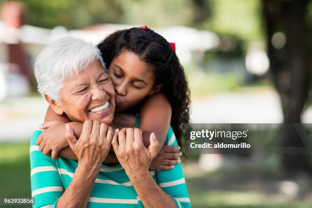 loving teen girl embracing and kissing grandmother - grandmother imagens e fotografias de stock