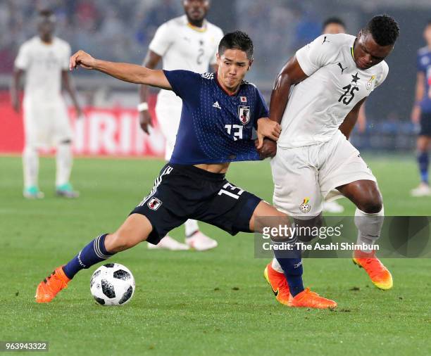 Yoshinori Muto of Japan and Rashid Sumaila of Ghana compete for the ball during the international friendly match between Japan and Ghana at Nissan...