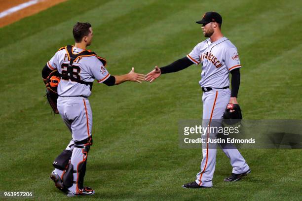 Relief pitcher Hunter Strickland and Buster Posey celebrate their 7-4 victory against the Colorado Rockies at Coors Field on May 30, 2018 in Denver,...
