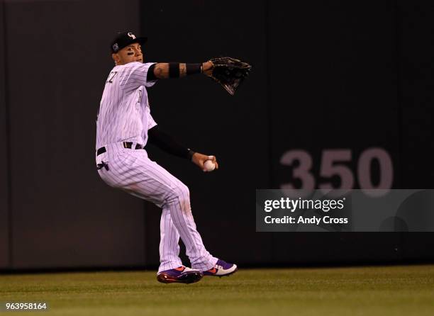 Colorado Rockies right fielder Carlos Gonzalez winds up and throws home, holding San Francisco Giants second baseman Kelby Tomlinson at third in the...