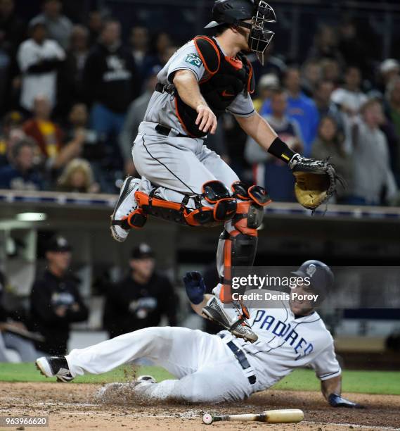 Realmuto of the Miami Marlins jumps over Matt Szczur of the San Diego Padres as he scores during the ninth inning of a baseball game at PETCO Park on...