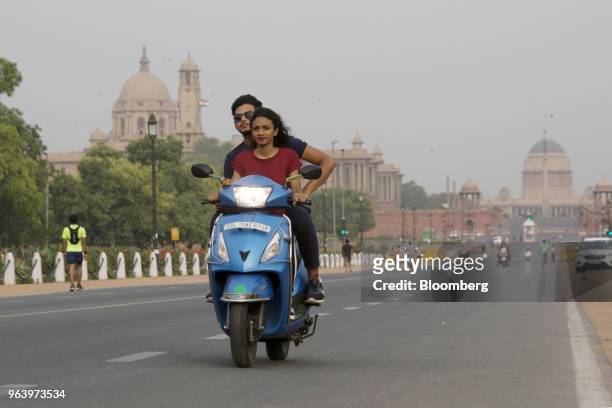 Motorcyclists travel on a scooter along King's Way boulevard flanked by the South Block of the Central Secretariat buildings, left, which houses the...