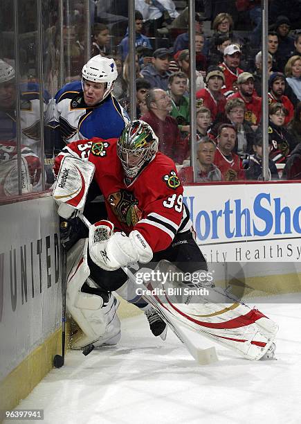 Goalie Christobal Huet of the Chicago Blackhawks and Brad Winchester of the St. Louis Blues fight for the puck on February 03, 2010 at the United...