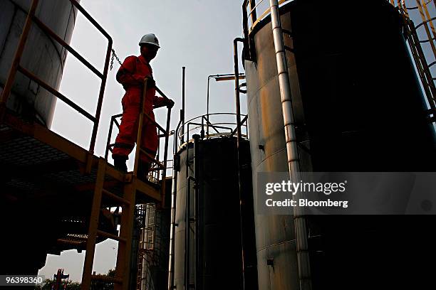 Exploration & Production Pcl production operator Kowan Boonruangjal looks out at crude oil storage tanks at PTTEP 1 Project site's U-Thong petroleum...