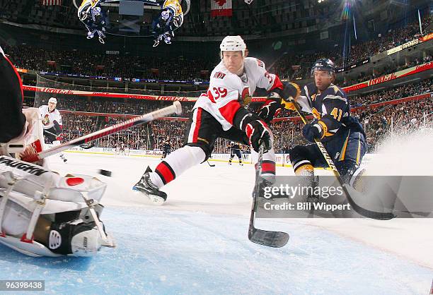 Clarke MacArthur of the Buffalo Sabres and Matt Carkner of the Ottawa Senators chase a rebound in front of goaltender Brian Elliott of the Senators...
