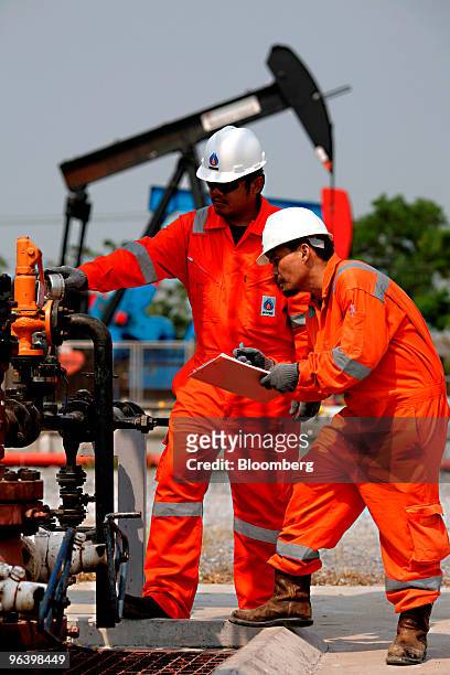 Exploration & Production Pcl production operators Kiattikul Roumsuk, left, and Narongrit Wankorn check the pressure of an oil pump at PTTEP 1 Project...