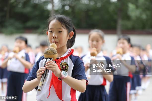 Students of an experimental primary school participate in cucurbit flute performance to welcome upcoming International Children's Day on May 30, 2018...