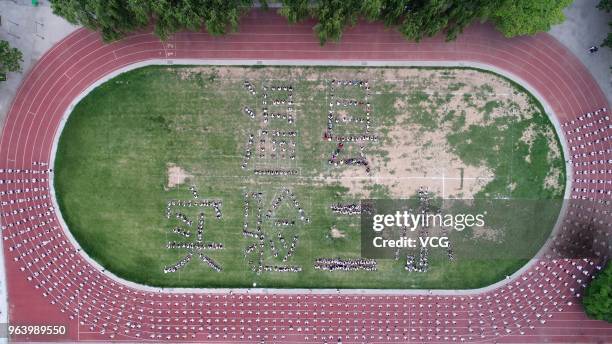 Aerial view of students posing as Chinese characters 'Wen County No.2 Experimental Primary School' while participating in cucurbit flute performance...