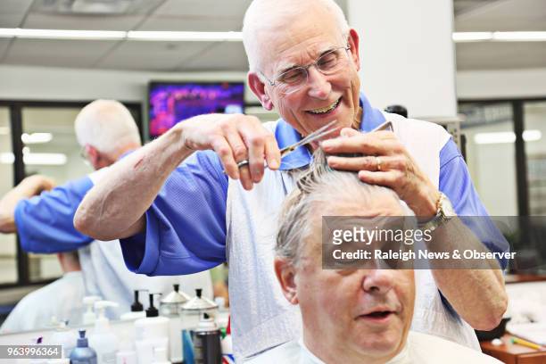 David Fowler, the main barber at Duke Barbershop in Durham, N.C., laughs with longtime customer Jim Thames on May 25, 2018. Duke Barbershop will...