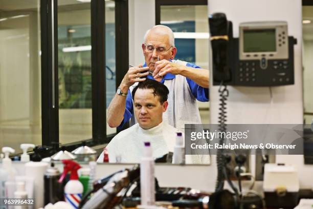 David Fowler, the main barber at Duke Barbershop in Durham, N.C., cuts longtime customer Adam Connor's hair on May 25, 2018. Duke Barbershop will...