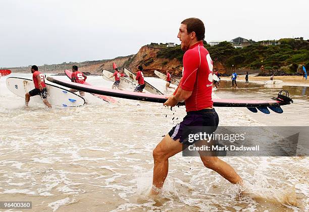Ryan Hoffman of the Storm races into the water with a surfboard during a Melbourne Storm NRL training session at Anglesea Beach on February 4, 2010...