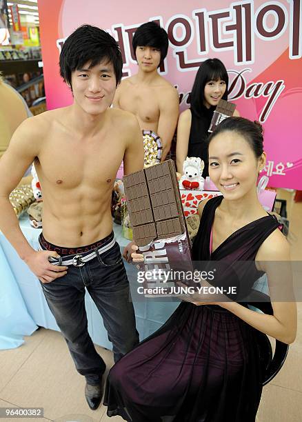 South Korean man poses topless, displaying his 'six-pack stomach' or as the promotion refers to it 'chocolate muscle', as a female colleague displays...