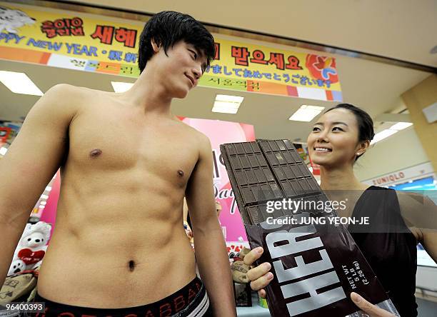 South Korean man poses topless, displaying his 'six-pack stomach' or as the promotion refers to it 'chocolate muscle', as a female colleague displays...