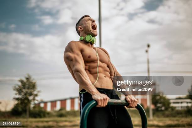 young man showing his muscles in the local park - angry bodybuilders posing stock pictures, royalty-free photos & images