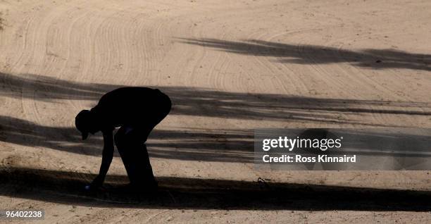 Ross Fisher of England on the checks his ball in the sand on the par four 14th hole during the first round the Omega Dubai Desert Classic on the...