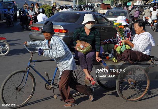 People sit on a bicycle-cart along a street in Phnom Penh on January 15, 2010. AFP PHOTO/TANG CHHIN SOTHY