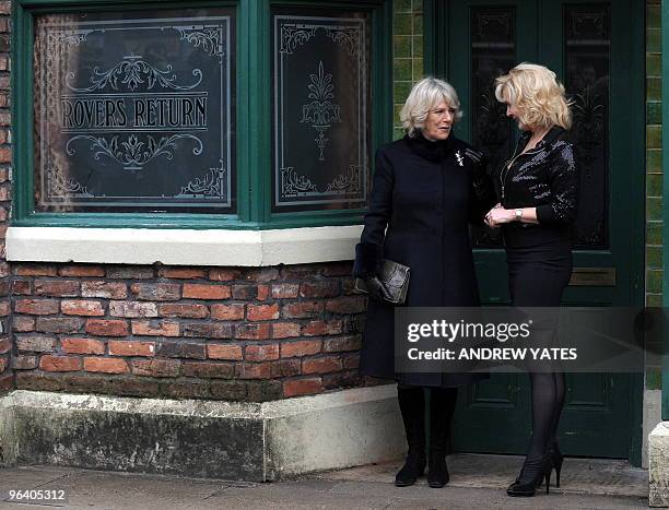 Camilla, The Duchess of Cornwall speaks with Beverley Callard who plays the role of landlady Liz McDonald as they leave the Rovers Return Pub during...