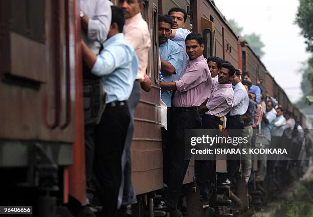 Sri Lankan commuters hold on to the sides of train coaches as they head to work in Kelaniya on January 19, 2010. AFP PHOTO/Ishara S. KODIKARA