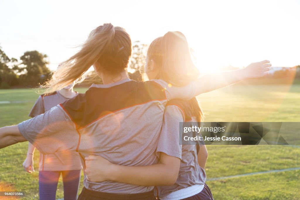 Team players embrace on the sports field in the evening light