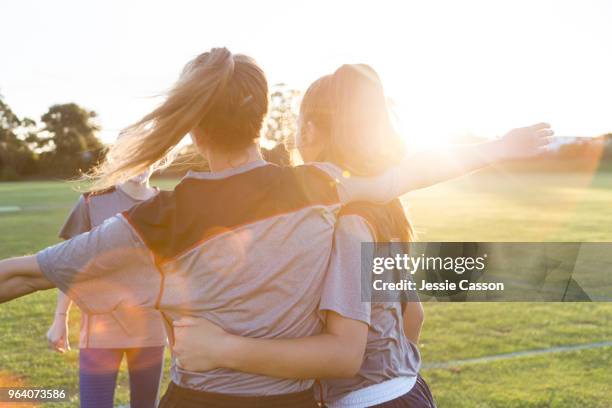 team players embrace on the sports field in the evening light - girls cricket team stock pictures, royalty-free photos & images
