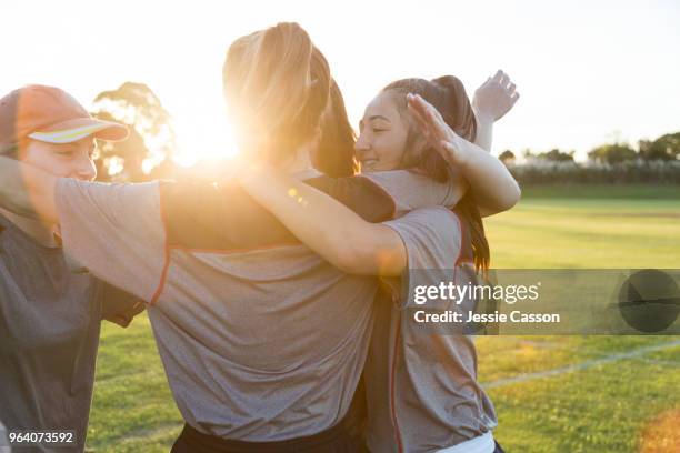 group hug - team players embrace on the sports field in the evening light - new zealand cricket stock pictures, royalty-free photos & images