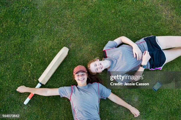 over head shot of two female cricket players lying on grass with sports gear - new zealand cricket stock pictures, royalty-free photos & images