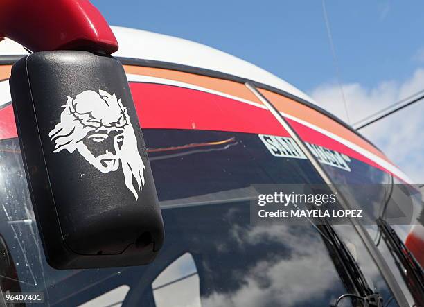 An image of Jesus is portrayed on a side-view mirror on a parked bus at a bus terminal in San Jose on January 30, 2010. AFP PHOTO / Mayela LOPEZ