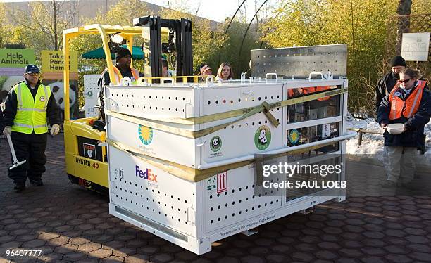 Workers move a specially designed crate holding Tai Shan, one of the Smithsonian National Zoo's giant pandas, prior to him leaving the zoo in...