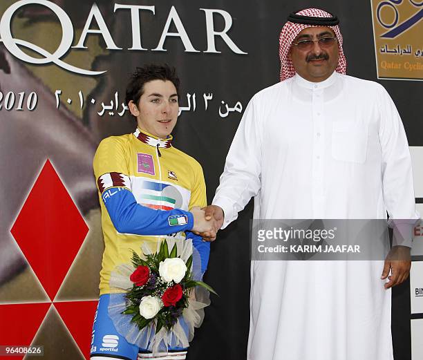 Sheikh Khaled bin Ali al-Thani, president of the Qatar Cycling Federation, shakes hands with Italy's Giorgia Bronzini after she won the second stage...