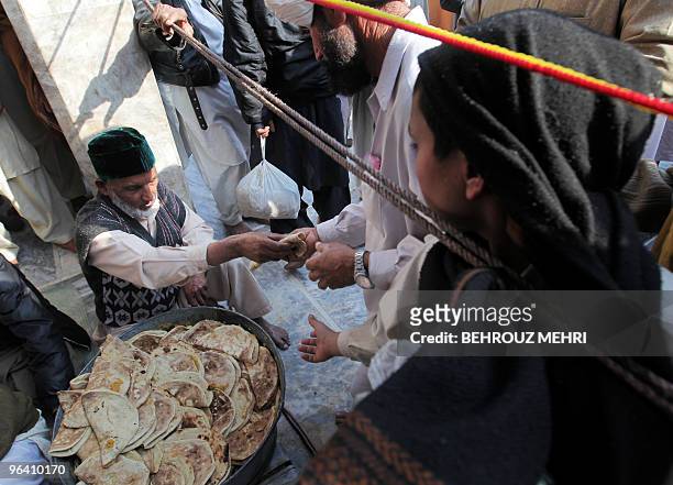 Pakistani Muslim man distributes donated food inside the Data Darbar, which holds the shrine of Saint Syed Ali bin Osman Al-Hajvery, popularly known...