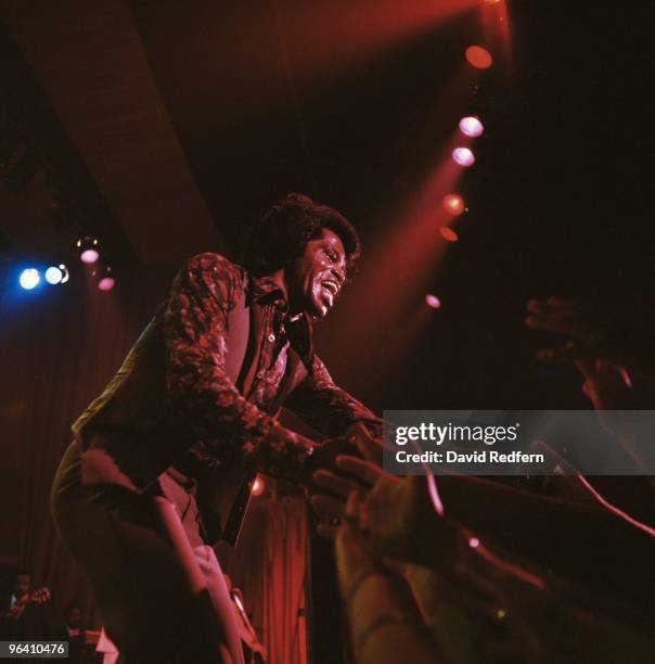 American soul singer and songwriter James Brown performs live on stage reaching out to touch the hands of audience members at The Venue in London in...