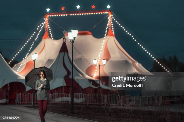 schöne mädchen mit regenschirm ist walking in der nacht - zirkuszelt stock-fotos und bilder