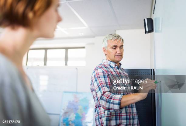 teacher writing on whiteboard in classroom - teachers pet stock pictures, royalty-free photos & images