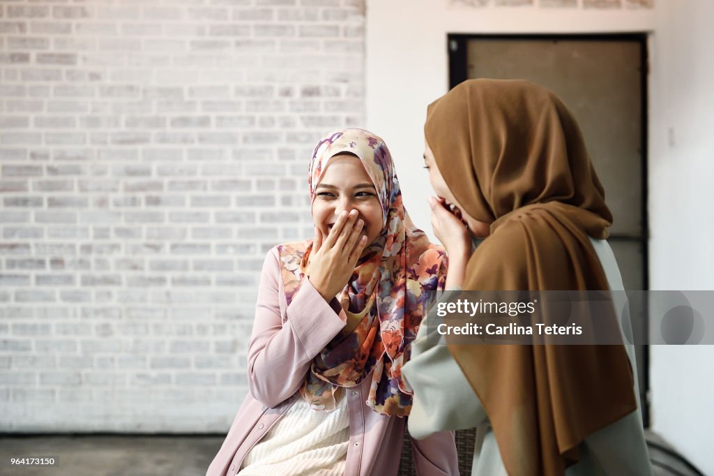 Two beautiful Malay ladies chatting indoors