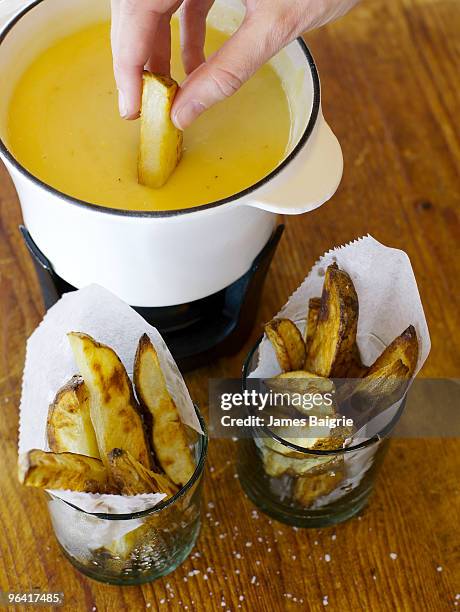 dipping a potato wedge in warm cheese - cheese wedge foto e immagini stock