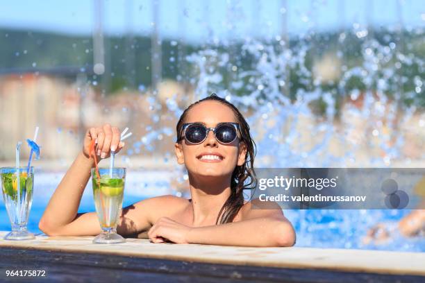 beautiful young woman drinking cocktail on swimming pool - rooftop pool imagens e fotografias de stock