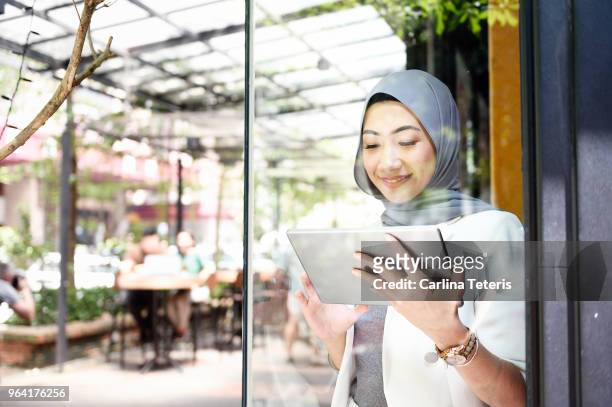 elegant muslim business woman working on a tablet through glass - 馬來西亞人 個照片及圖片檔