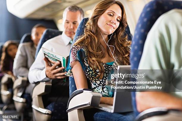 woman using computer on airplane - business class seat stockfoto's en -beelden