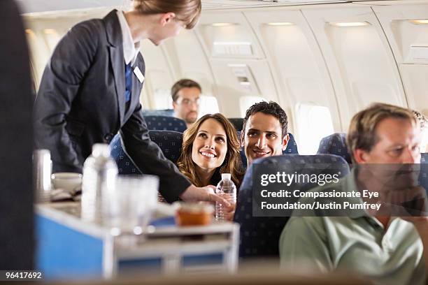 flight attendant serving customers on an airplane - flight attendant serving foto e immagini stock
