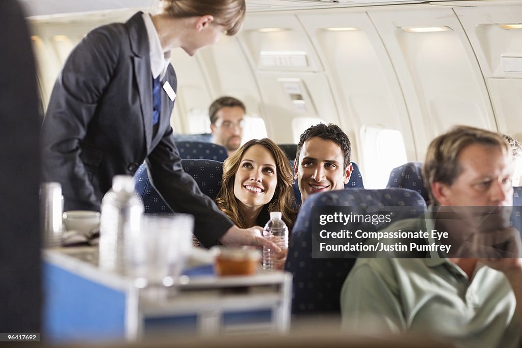 Flight attendant serving customers on an airplane