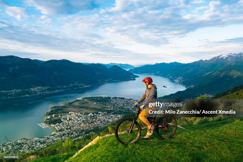 Mountain biker pauses to enjoy view over mountains, lake