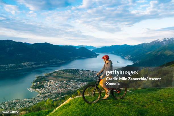 mountain biker pauses to enjoy view over mountains, lake - locarno stock-fotos und bilder