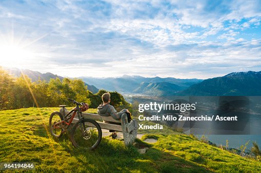 Mountain biker relaxes to enjoy view over mountains, lake