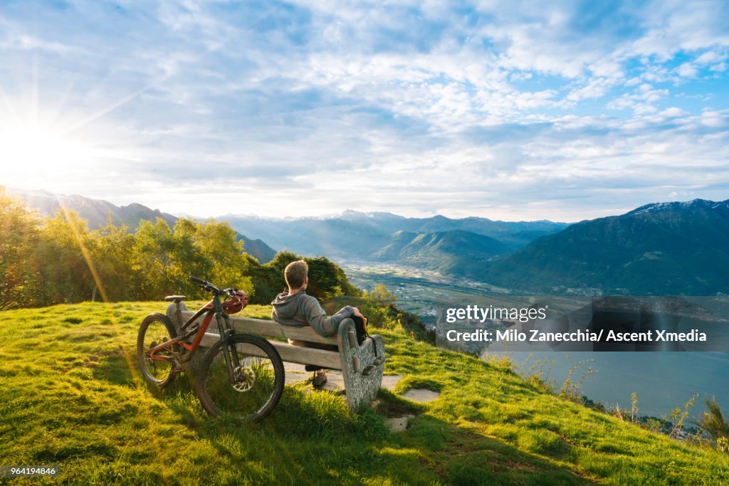 Mountain biker relaxes to enjoy view over mountains, lake