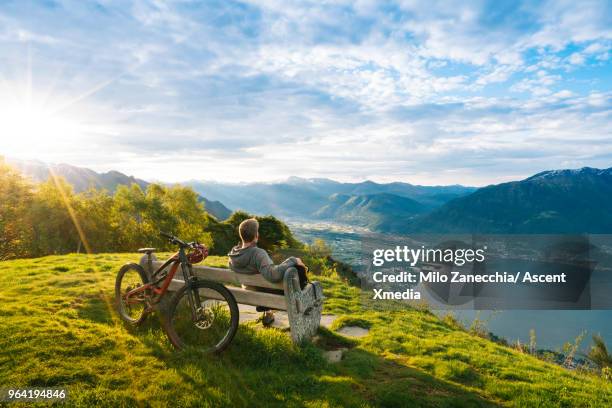 mountain biker relaxes to enjoy view over mountains, lake - lake sun stock pictures, royalty-free photos & images