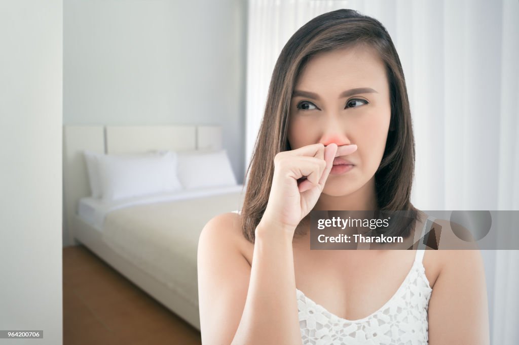 Aziatische dames in het wit jurk gevoel onwel en niezen bij slaapkamer.