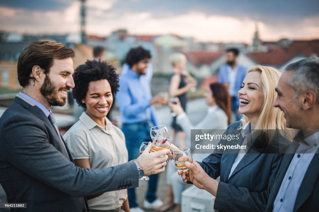 Cheerful business colleagues toasting with alcohol at the outdoor party.
